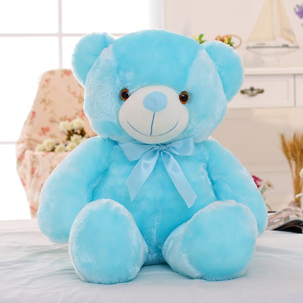 Blue teddy bear with a bow on a white surface