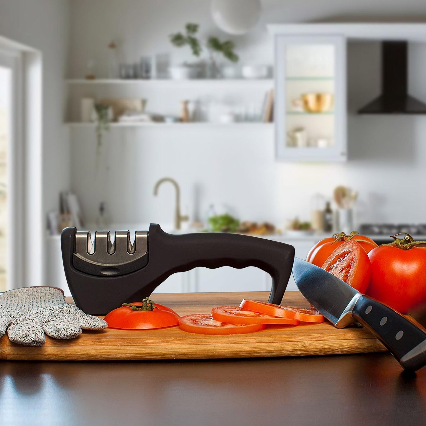 Knife sharpener on a cutting board with sliced tomatoes and a kitchen in the background