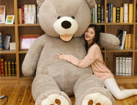 Woman sitting on a large gray teddy bear in a room with bookshelves.