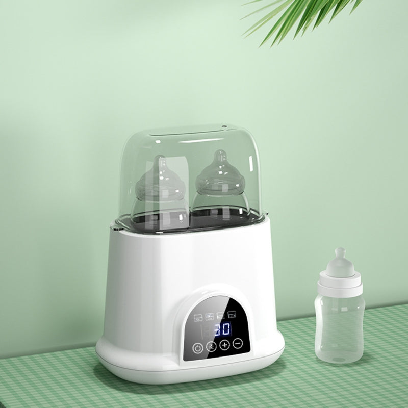 Baby bottle warmer with a digital display on a green surface against a light green wall.