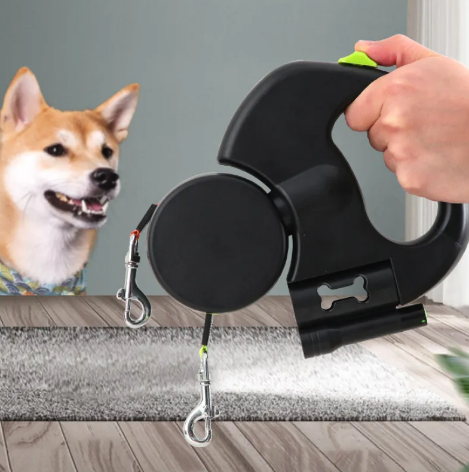 Retractable dog leash with a hand holding it, next to a dog on a wooden floor.