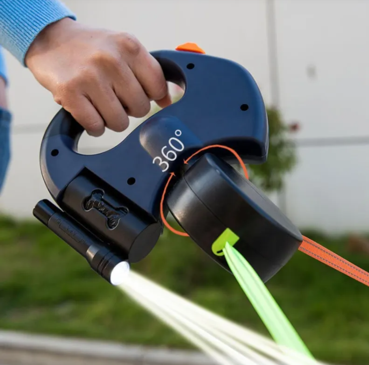Hand holding a black 360-degree spray nozzle with water being sprayed outdoors.