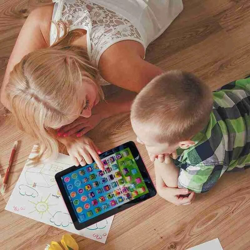 Woman and child interacting with a tablet on a wooden floor