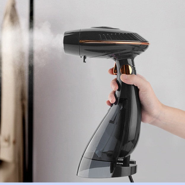 Hand holding a black handheld steamer against a light gray background