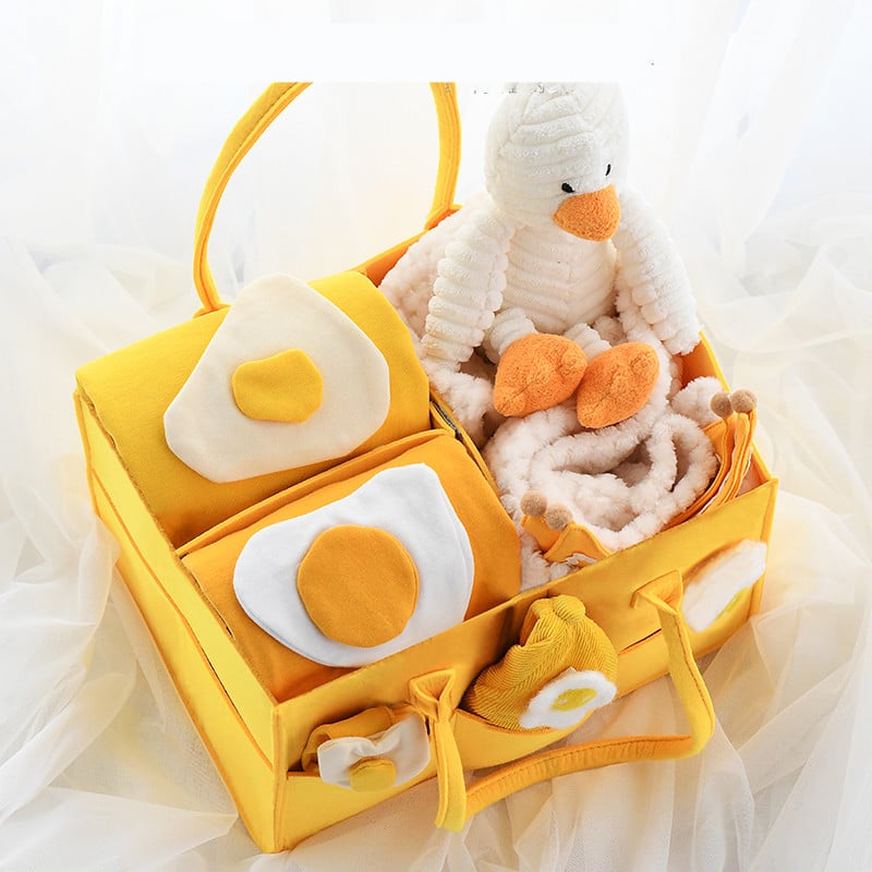 Yellow basket with plush toys including a duck and eggs on a soft white background