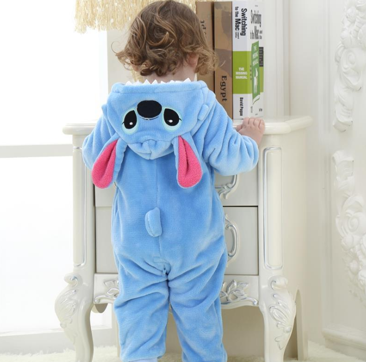 Child wearing a blue cartoon character onesie in a room with white furniture.