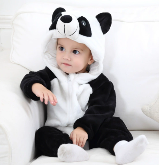 Baby wearing a panda onesie sitting on a white couch.